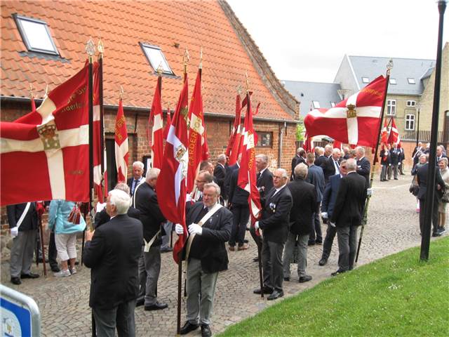 Fanerne samles foran kirken.